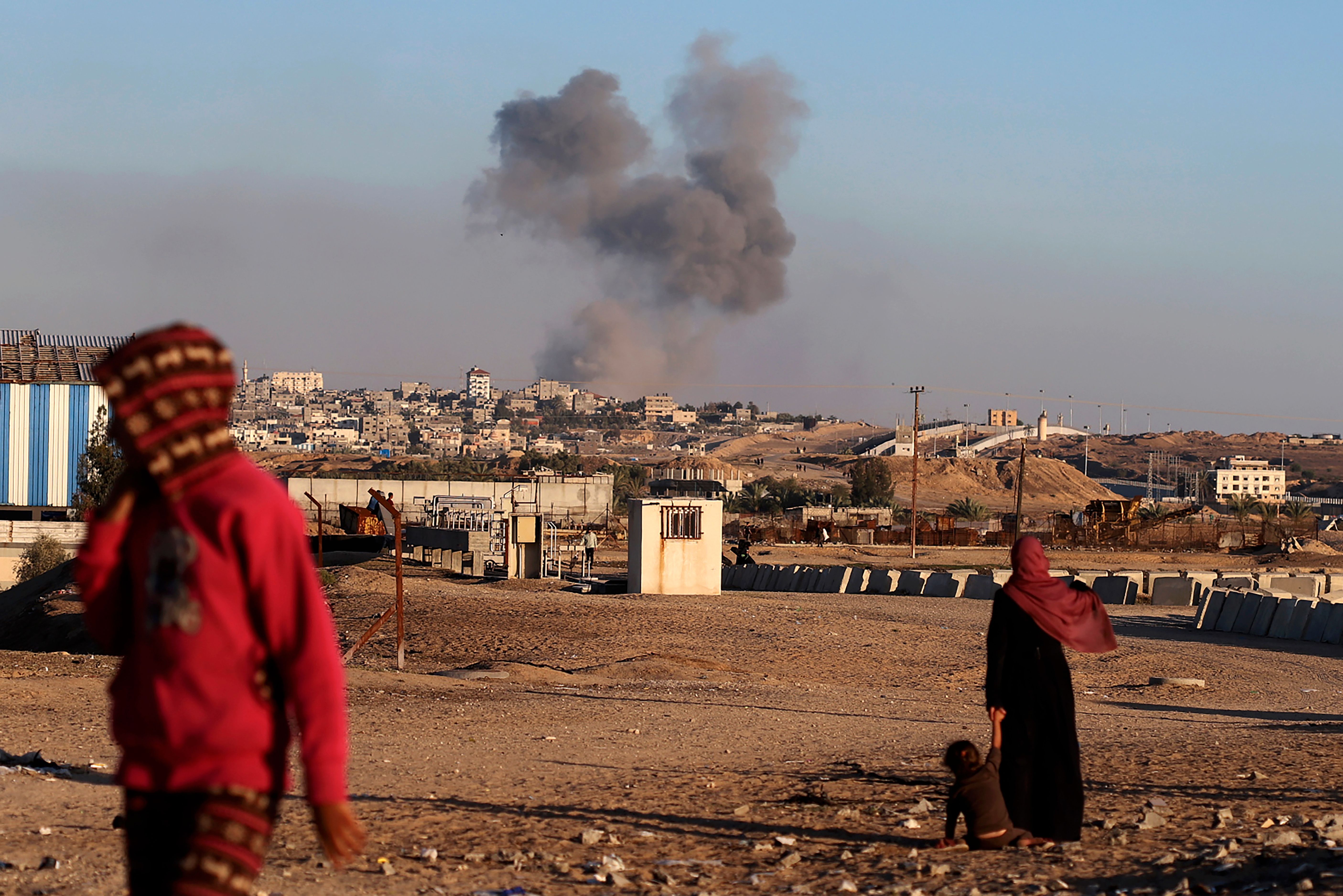 Palestinier blickar mot rök som stiger efter ett israeliskt flyganfall mot gränsområdet vid Rafah. Bilden togs under tisdagen.